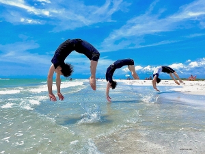 Mens de gjør seg klare for showene i Florida, er et avslappende besøk på stranden en nødvendighet. De mannlige danserne tar baklengs salto inn i bølgen, nesten som delfiner som hopper over bølgene.